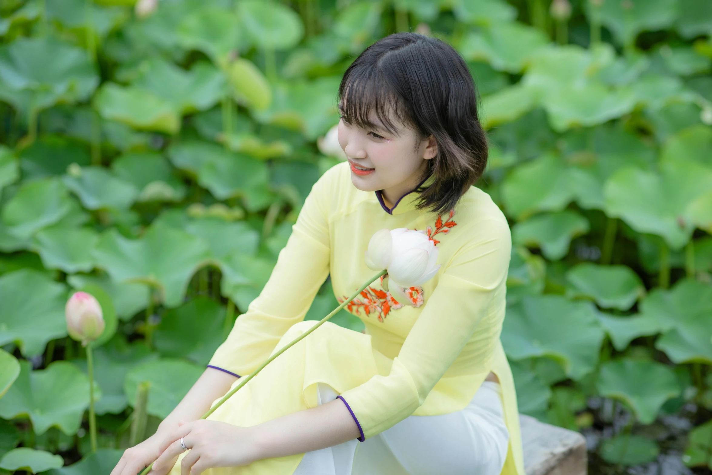 a woman sitting down next to waterlily plants