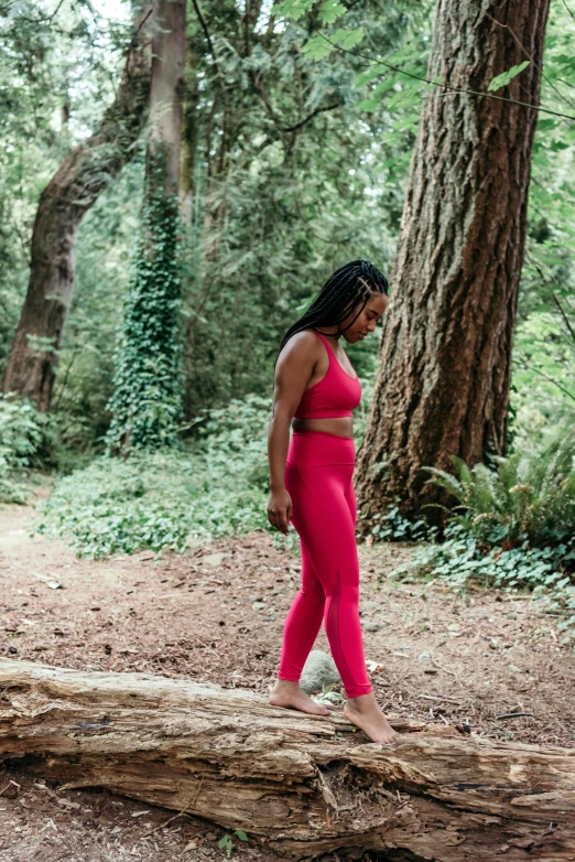 a woman standing in the woods in pink outfit