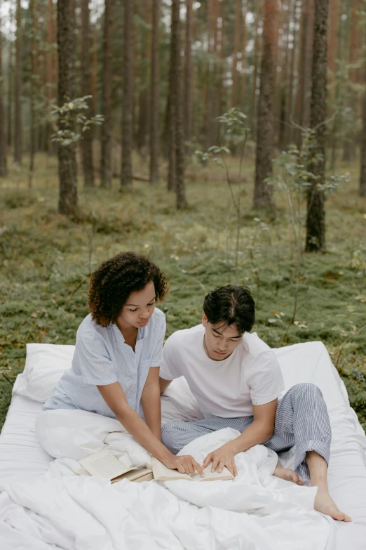 two people sitting on a bed in the woods
