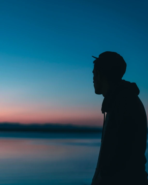 a man standing in front of the ocean watching the sunset