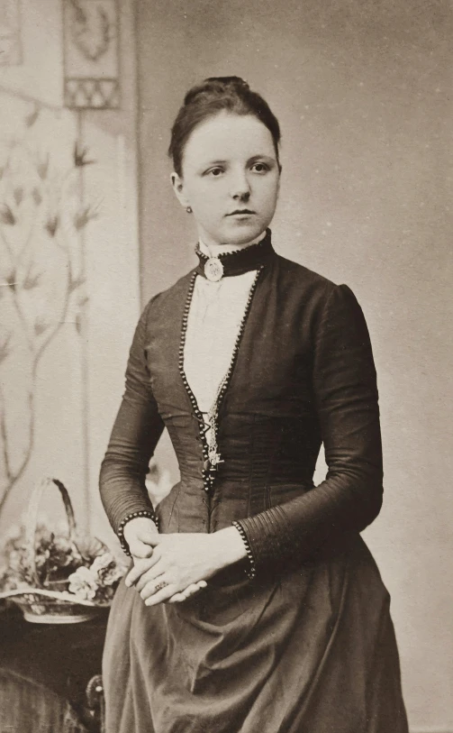 a woman in an elegant dress and hat standing