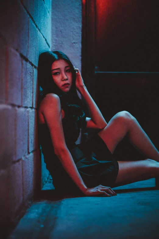 a girl sits on the floor against a brick wall