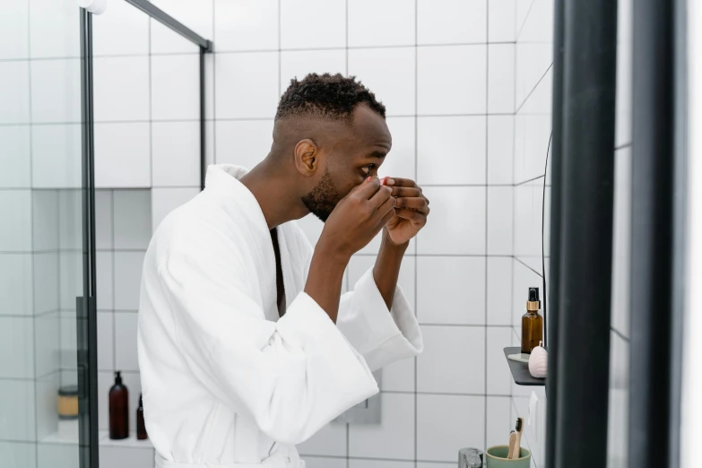 a man in a white robe brushes his teeth