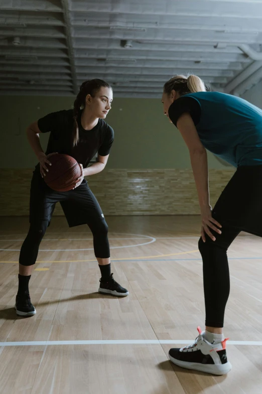 two girls are playing basketball on the court