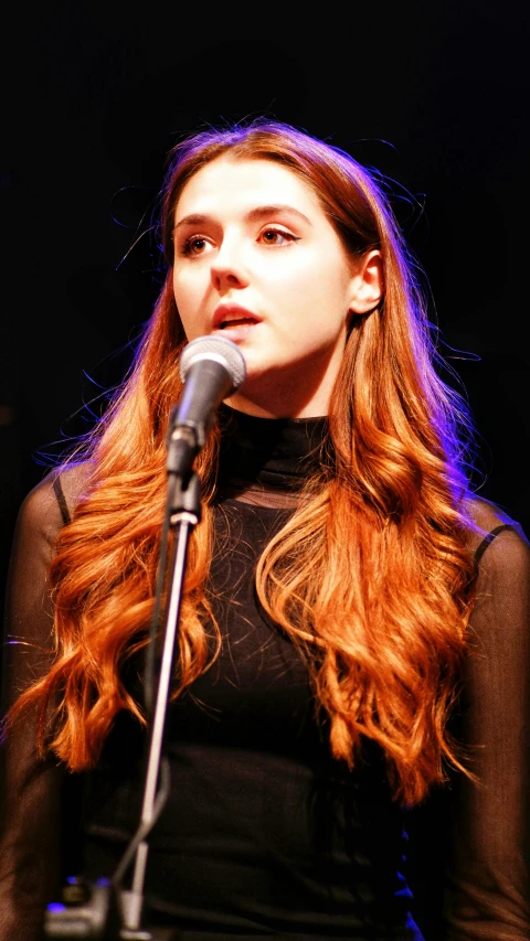 the woman is holding a microphone and singing