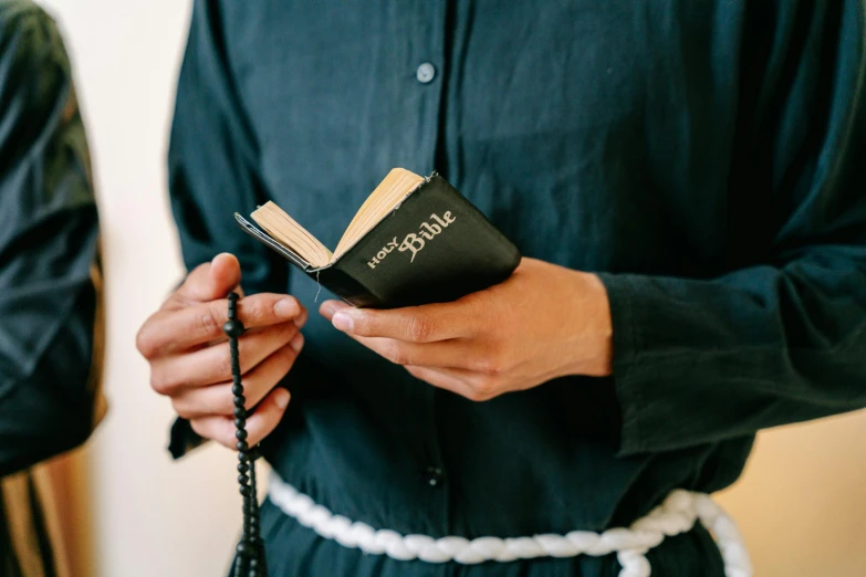 an individual is holding a small black book in their hands