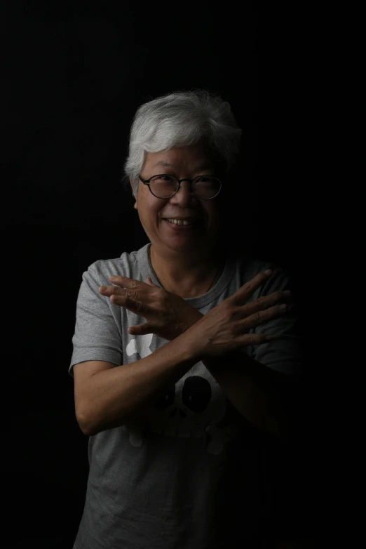 an older lady smiling and gesturing with her arms crossed