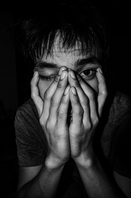 a man covers his eyes with hands while staring into the camera