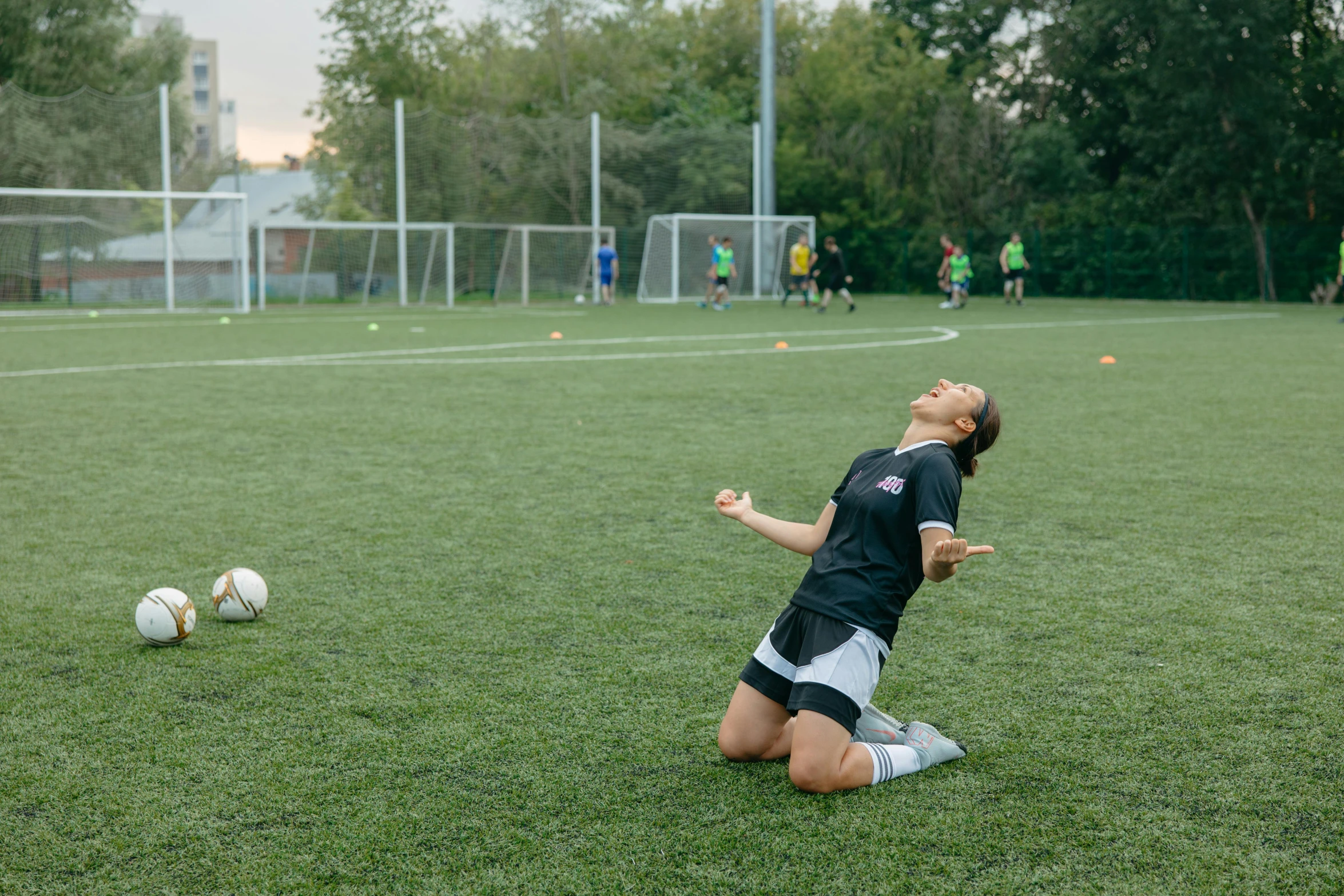 woman kneeling on the ground, reaching for a soccer ball