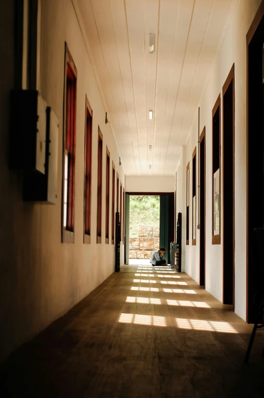 empty corridor with sun shining down on two people on either side