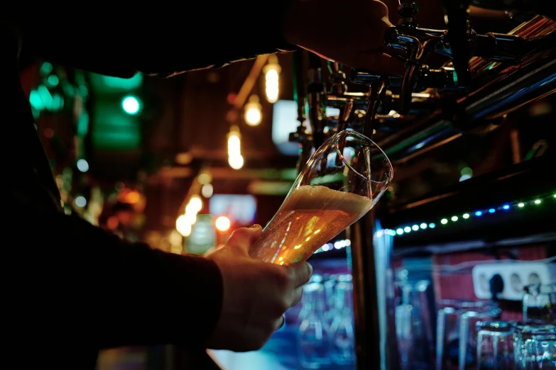 a person is holding up a glass of beer