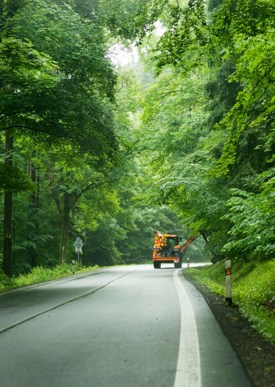 a truck traveling down a curvy road in the middle of a wooded area