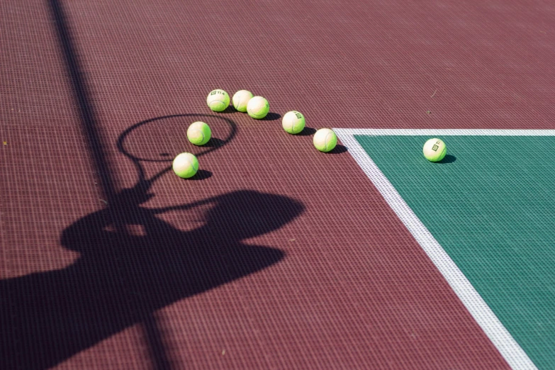 several tennis balls and racket laying on the court