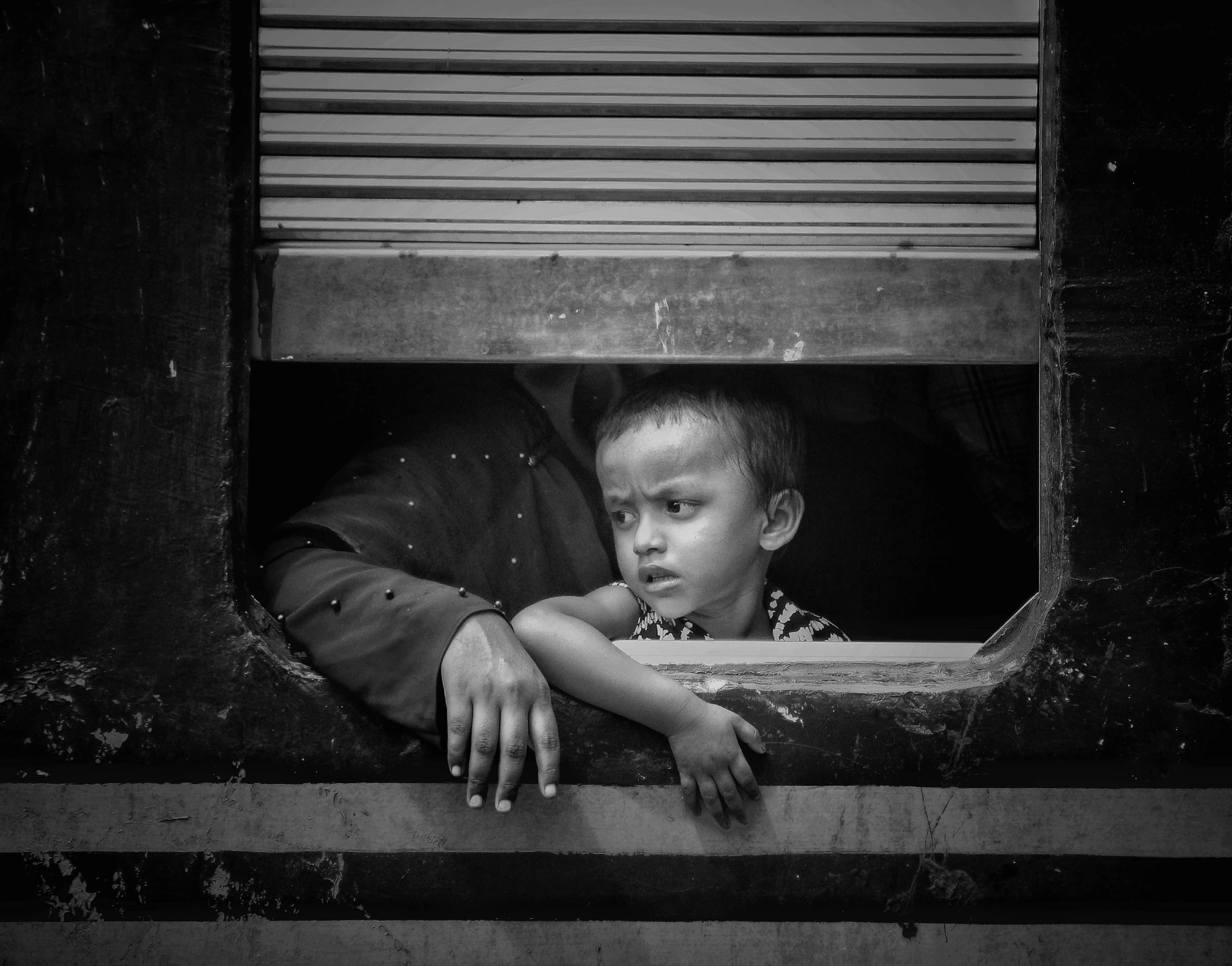 two small boys standing outside a window looking out