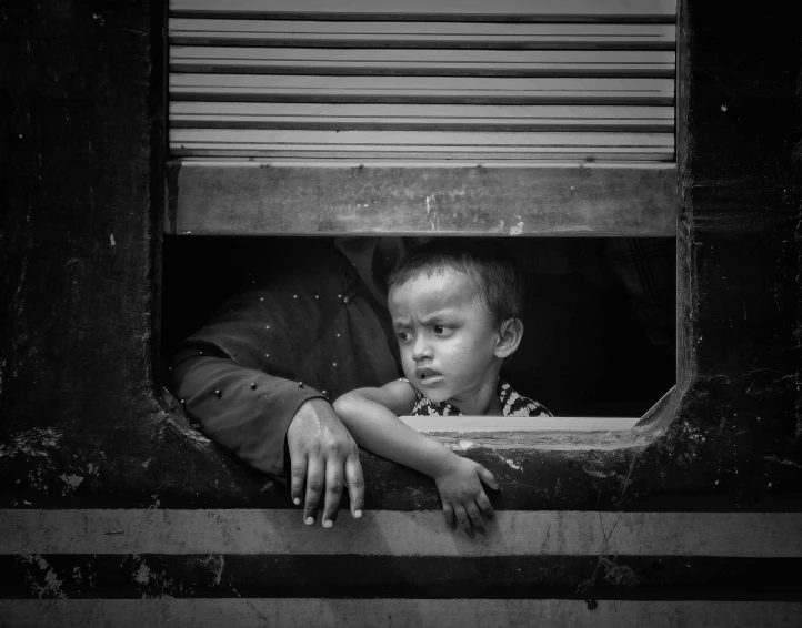 two small boys standing outside a window looking out