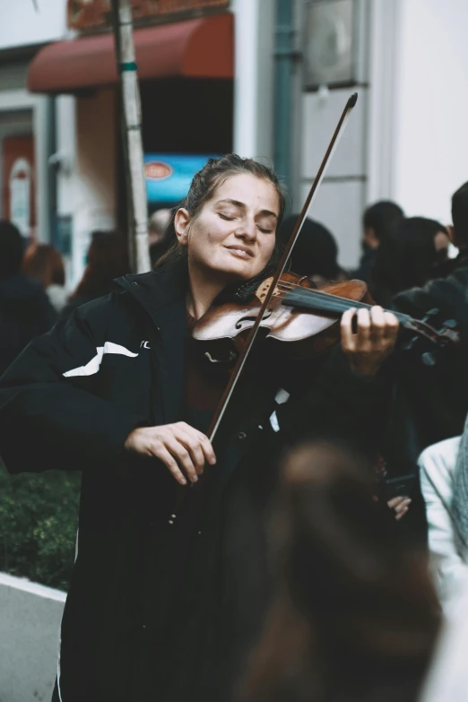 a woman playing a violin on a busy street