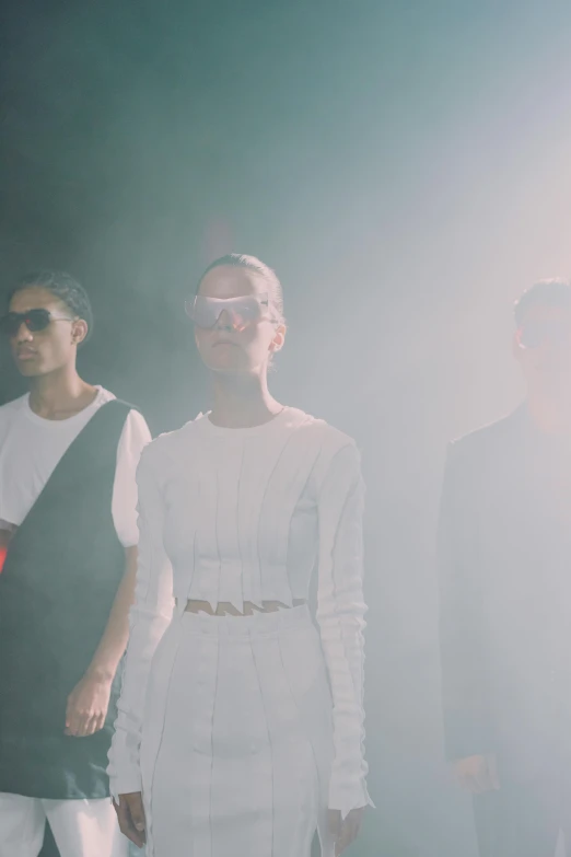 three people standing in a room with sun glares on them