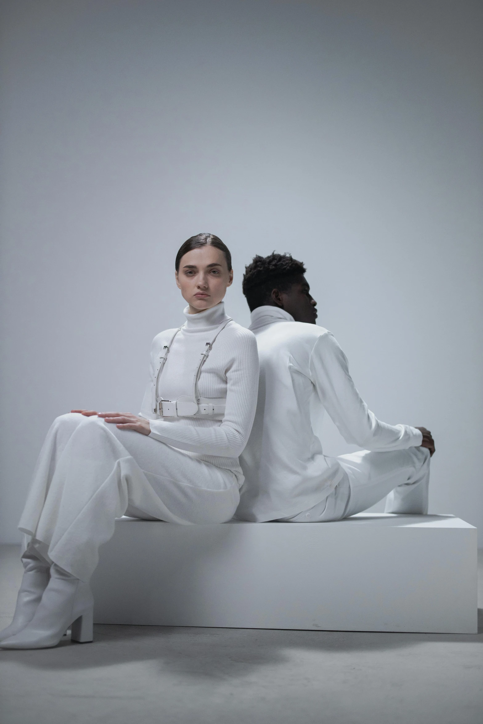 a man and woman sitting next to each other in white outfits