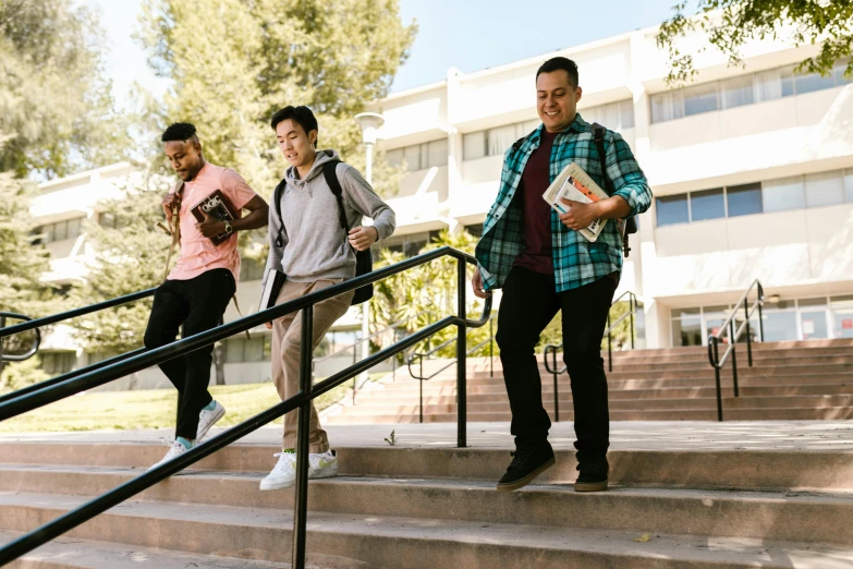 three men are standing on the stairs and one of them is carrying books