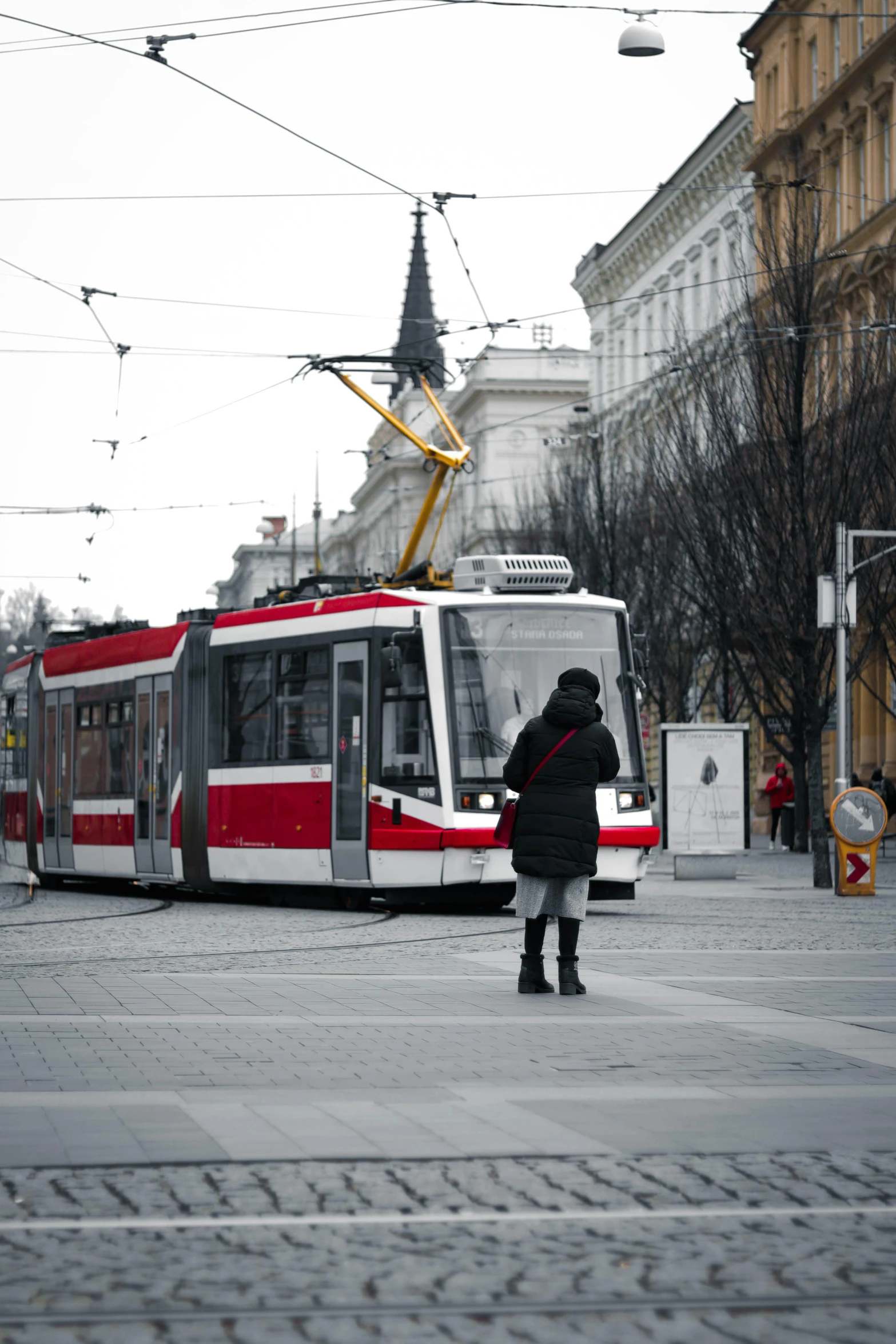 the passenger bus is traveling in front of the woman