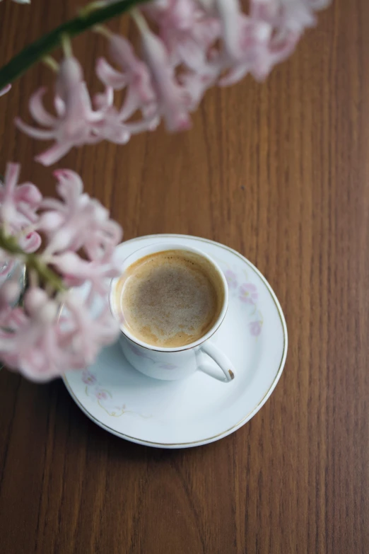 coffee cup on saucer surrounded by pink flowers