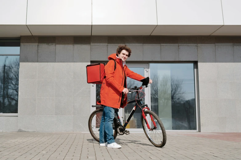 man in orange jacket next to a bicycle