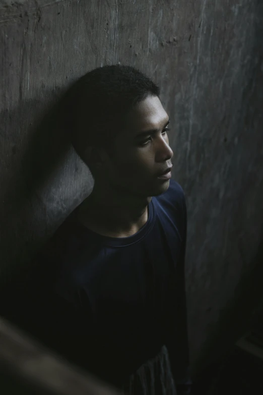 a man with short hair is standing up against a wall