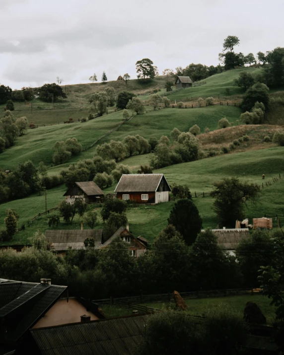 a field with houses in the distance and green hills