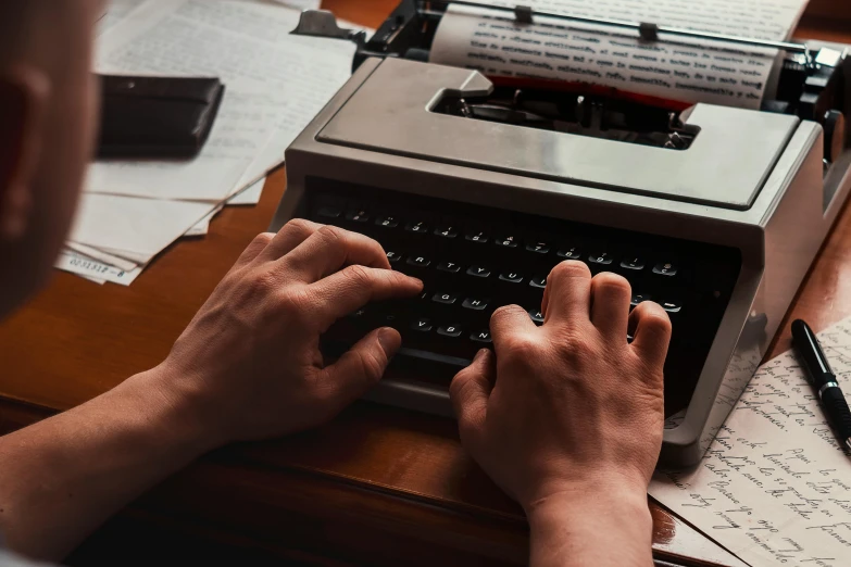 someone working on an old - school typewriter at a desk