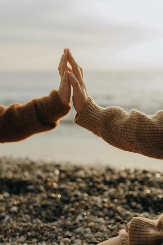 two people doing hands in the sand with one person reaching for an object