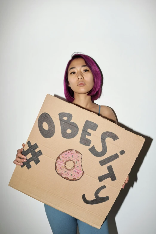 a woman with bright pink hair and a cardboard sign holding a doughnut on the front