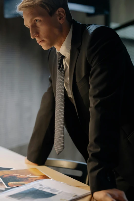 an old man in a black suit sitting at a desk