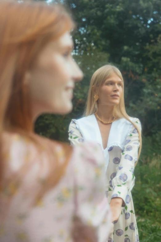 two women standing next to each other in front of trees