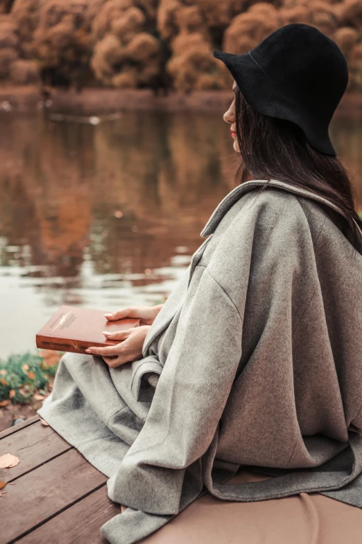 a woman is sitting on a bench reading a book