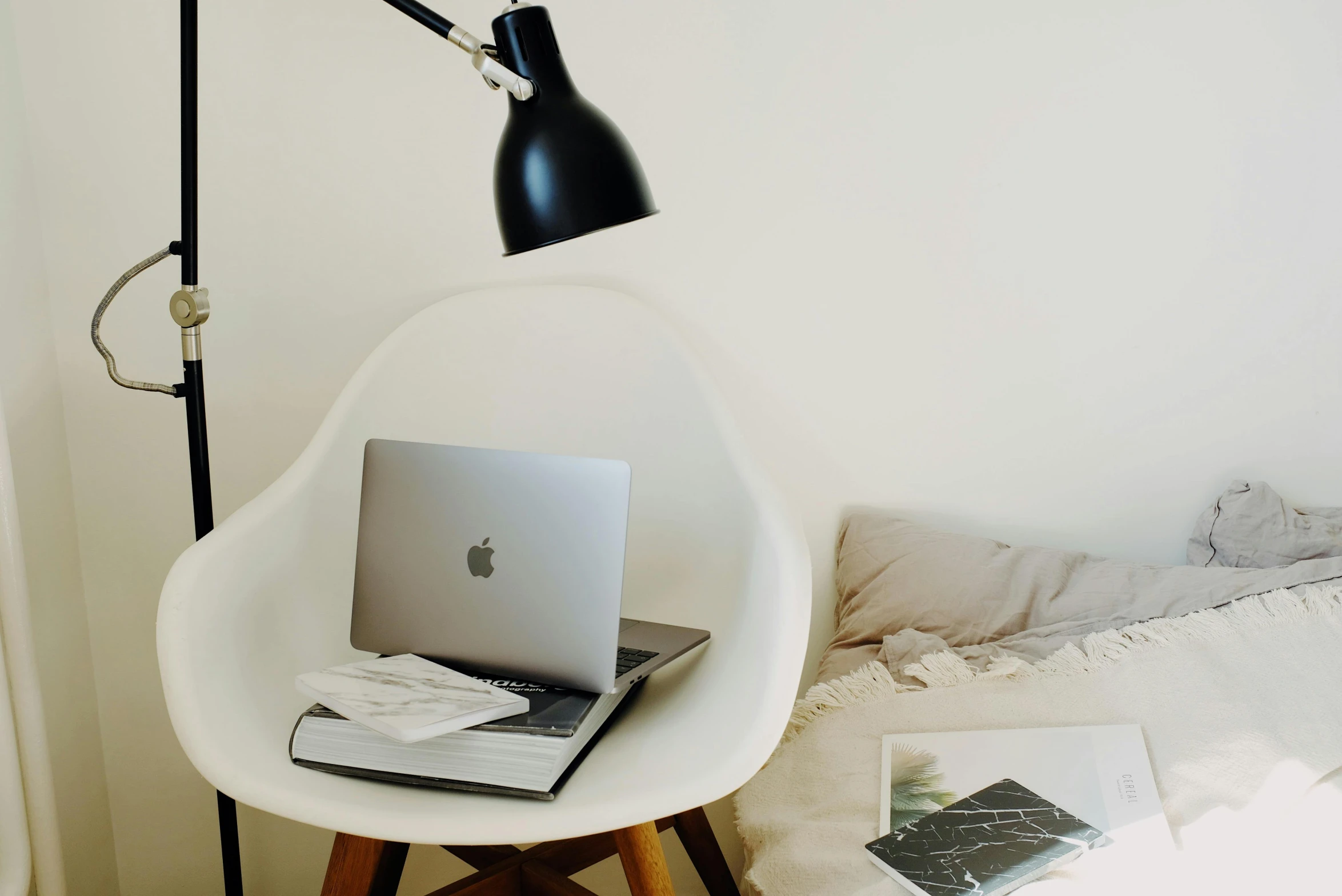 a laptop computer sitting on top of a chair next to a lamp