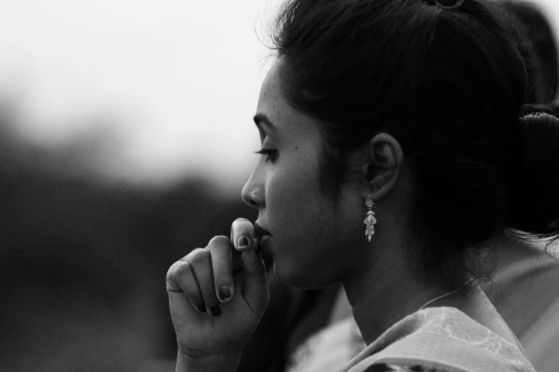 an asian woman holds her finger under her lip