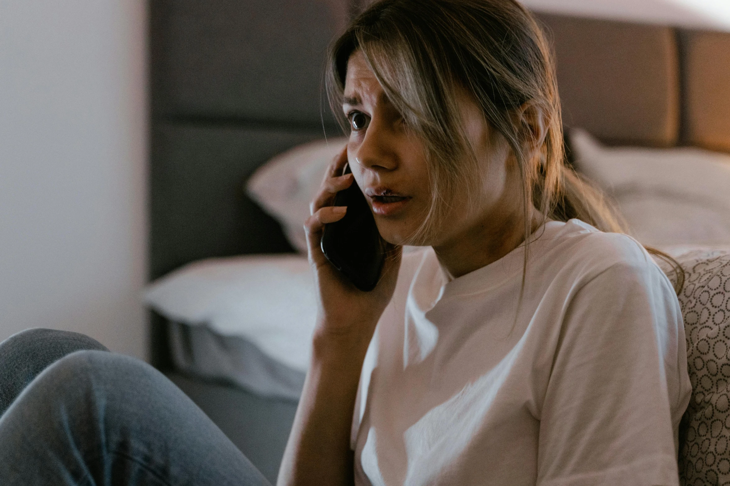 a close up of a woman sitting on a couch talking on a phone