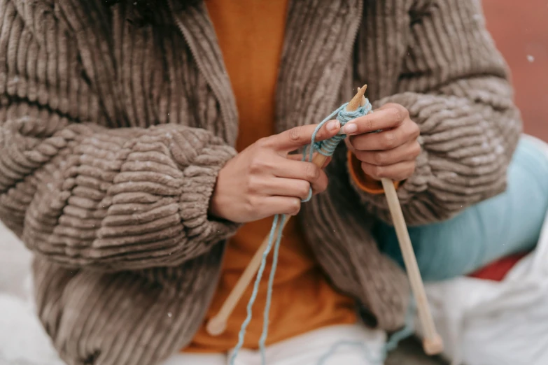 a person holding yarn and a wooden skewer