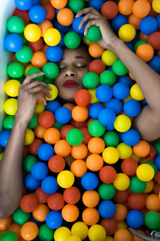 a woman is surrounded by many balls in a tub