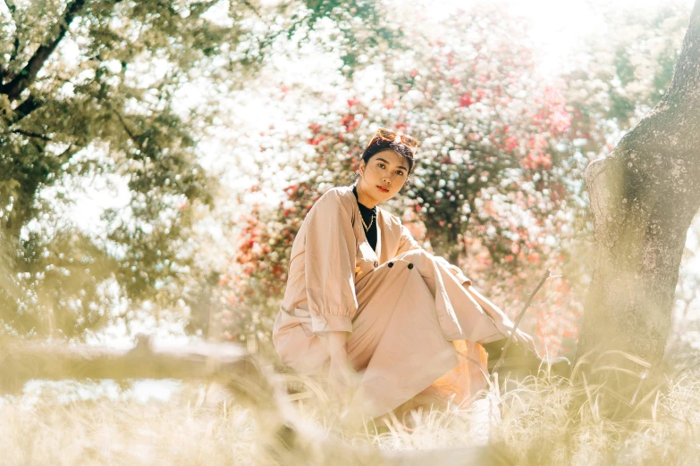 a woman sitting under a tree in a grass field