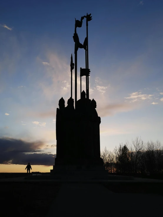 silhouetted people walking around an old clock tower at twilight