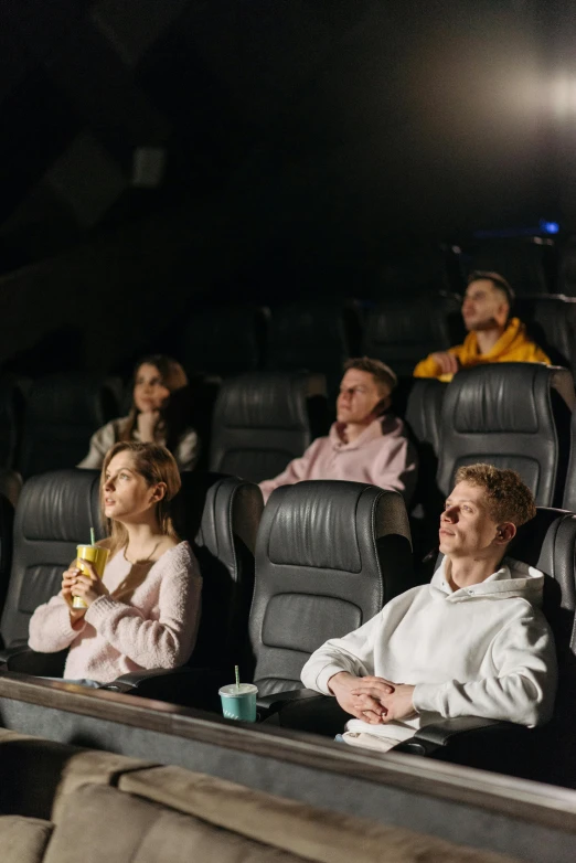 a group of people sit in a darkened room watching the film