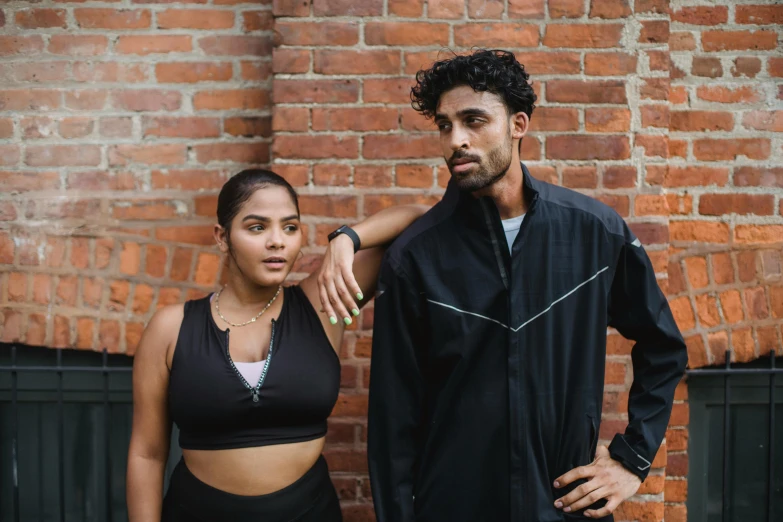 a man and woman posing by a brick wall