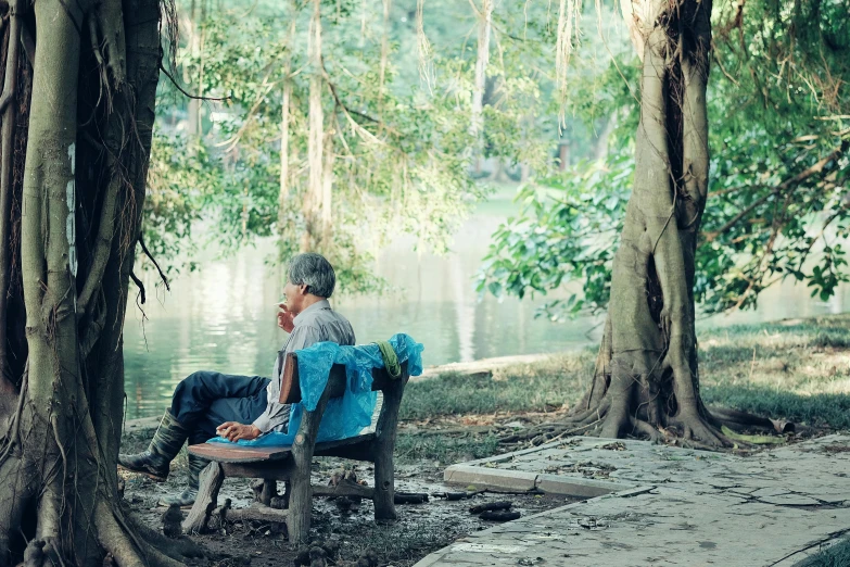 a woman is sitting in a chair next to some trees