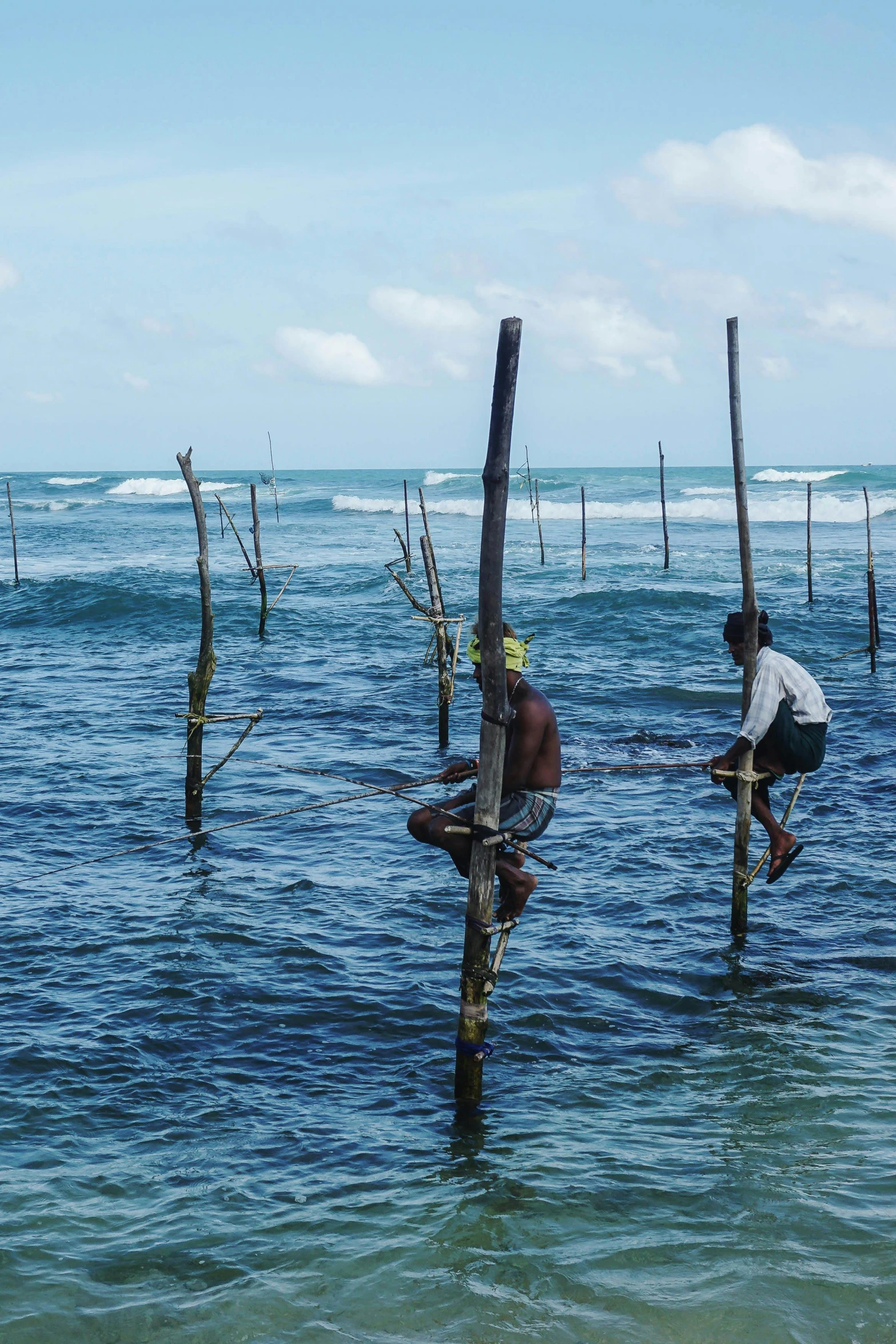 two people who are sitting on wooden poles