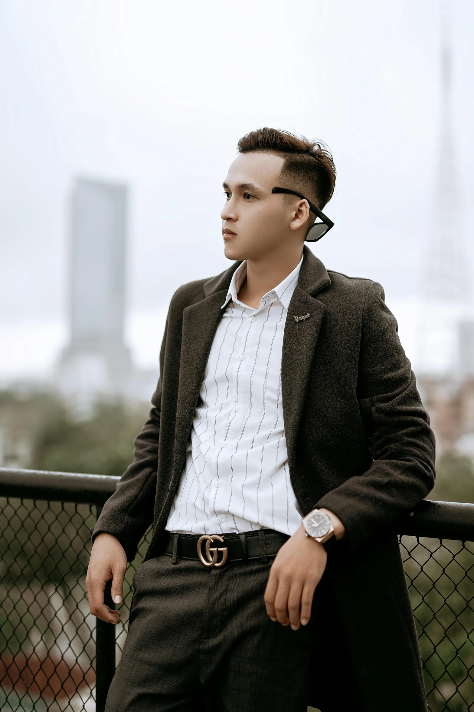 the young man poses in front of the fence