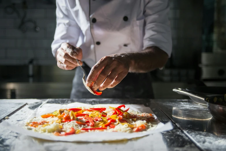 chef preparing vegetable pizza on a table in a kitchen