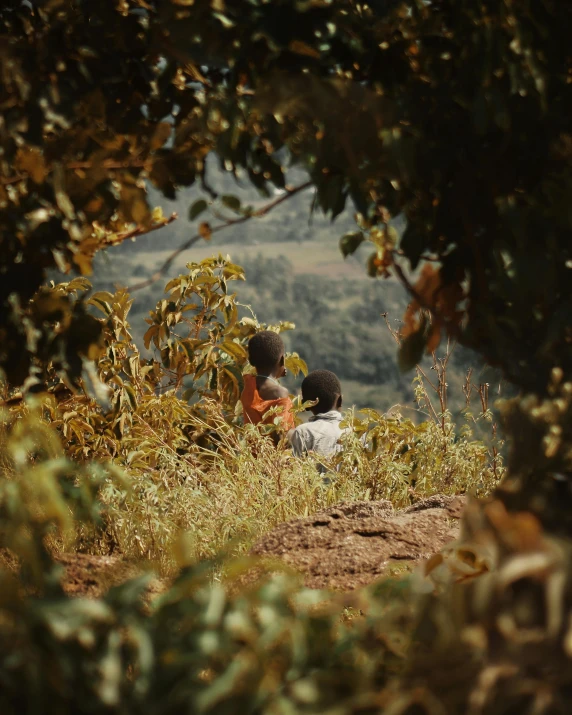 two children sitting and one has a green and yellow erfly