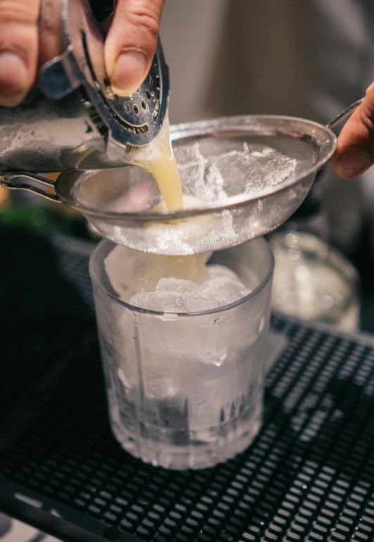 someone pours a liquid into a glass on the counter