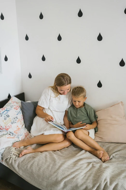 mother reading book to her two sons on a bed